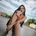 Fashionable woman sitting and pointing in a casual urban setting. Summer vibes.