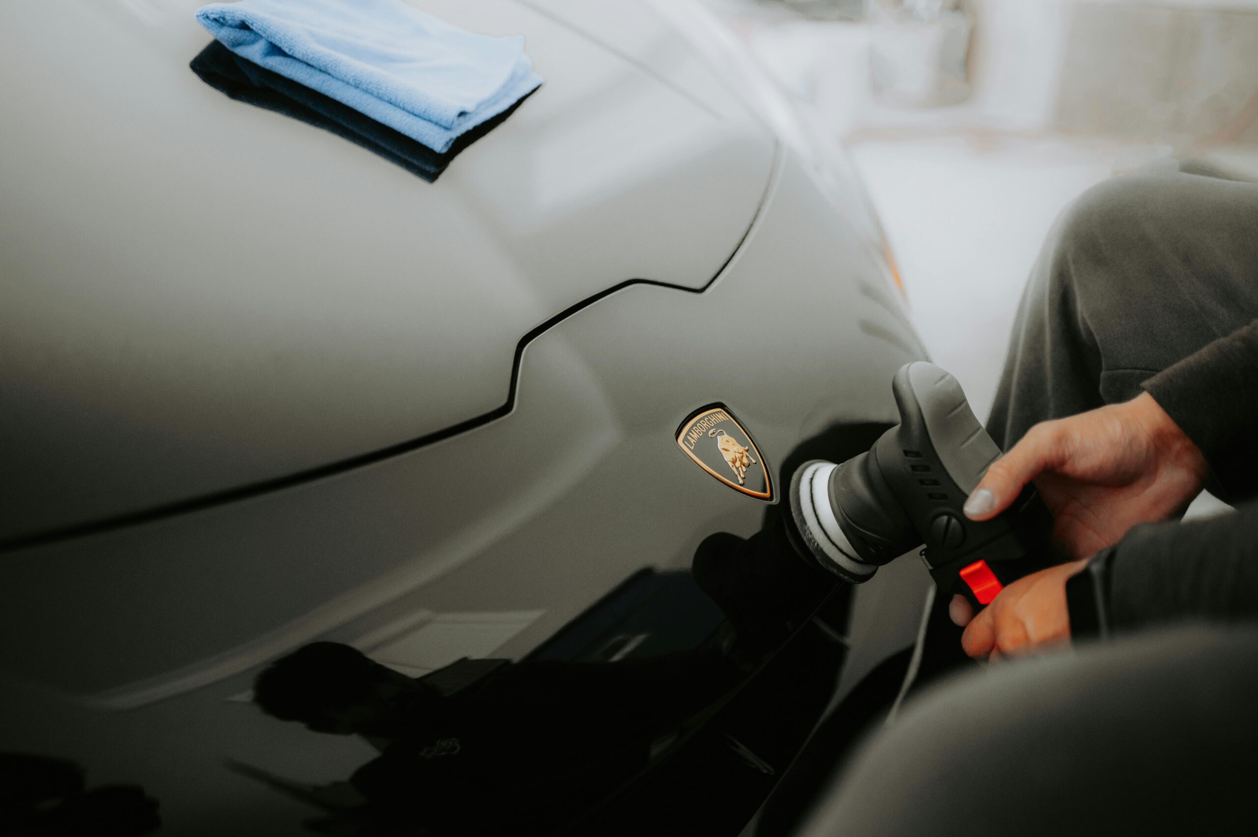 Detailed shot of a Lamborghini being polished, showcasing an automotive care process in a garage.